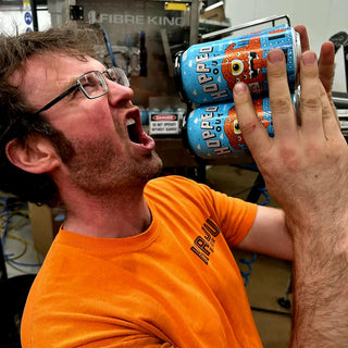 Man holding four pack of KAIJU Beers seasonal release of Hopped Out Red